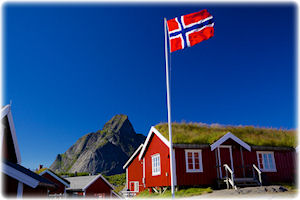 Das Königreich Norwegen ist stolz auf seine Kultur und die Natur. Eine rote Hütte mit Grasdach und einer Flagge von Norwegen im Vordergrund.