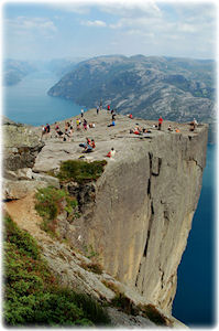 Dieser Felsen erlaubt einen besonders genialen Ausblick auf die unberührte Natur. Eine hervorstehende Klippe, auf der sich Menschen tummeln. Grandioser Blick auf den fjord.